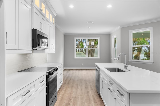 kitchen with crown molding, light countertops, a sink, tasteful backsplash, and appliances with stainless steel finishes
