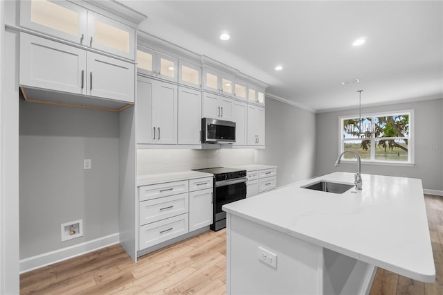 kitchen with crown molding, stainless steel microwave, a center island with sink, a sink, and black range with electric stovetop