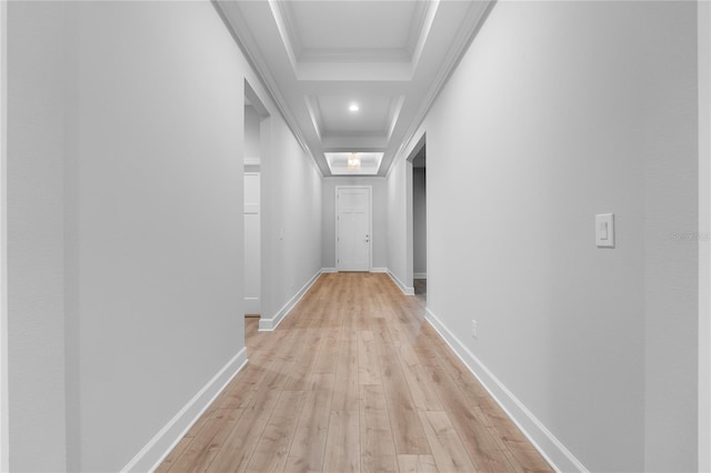 hall featuring crown molding, light wood-style floors, a tray ceiling, and baseboards