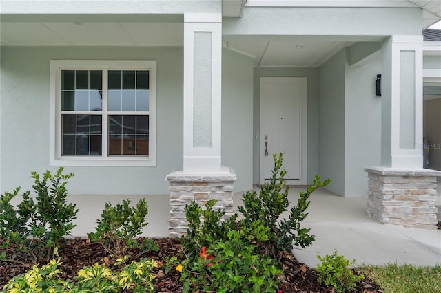 entrance to property featuring stucco siding and a porch