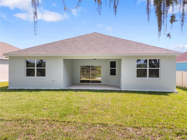rear view of house with a patio area, stucco siding, a yard, and a shingled roof