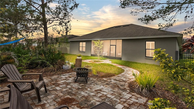 back house at dusk featuring a patio area and a fire pit