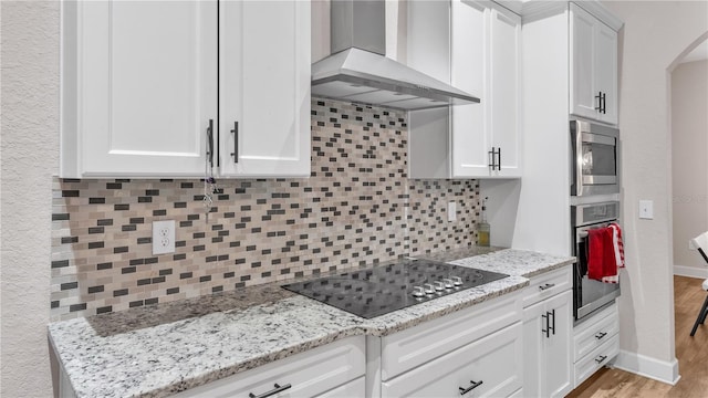 kitchen with light hardwood / wood-style floors, appliances with stainless steel finishes, tasteful backsplash, and wall chimney exhaust hood