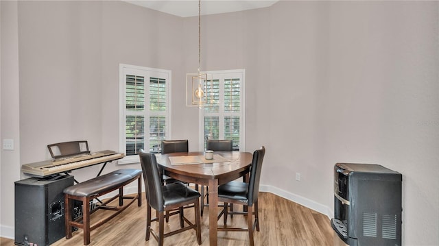 dining area with a high ceiling, light hardwood / wood-style floors, and an inviting chandelier