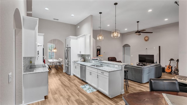 kitchen with white cabinets, light hardwood / wood-style flooring, backsplash, and light stone countertops