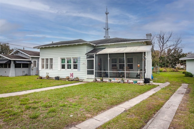 view of front of home featuring a sunroom and a front lawn