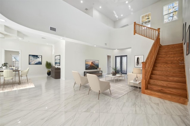 living room featuring visible vents, a towering ceiling, marble finish floor, stairs, and french doors