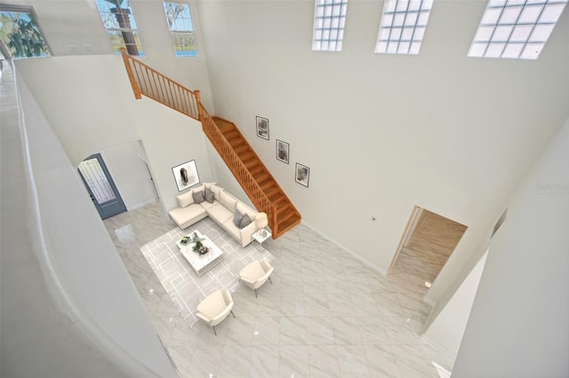 living room with a towering ceiling, marble finish floor, and stairway