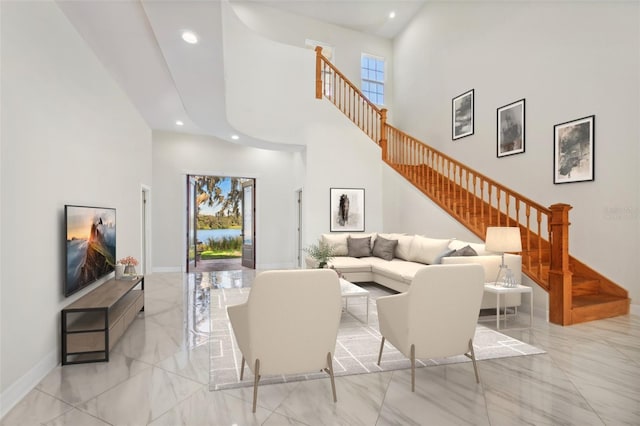 living room featuring a towering ceiling, marble finish floor, and stairway