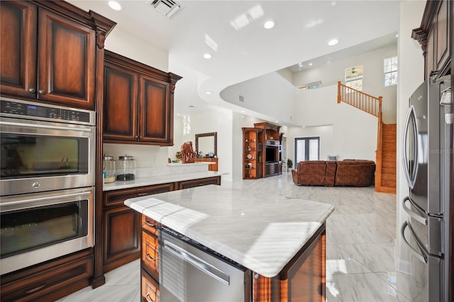 kitchen with light stone counters, visible vents, open floor plan, marble finish floor, and appliances with stainless steel finishes