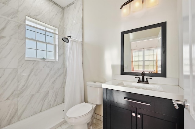 bathroom with tiled shower, vanity, and toilet