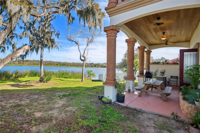 view of yard with ceiling fan, a patio area, and a water view