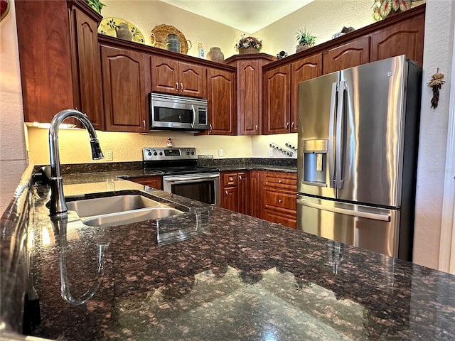 kitchen with dark stone counters, appliances with stainless steel finishes, and sink