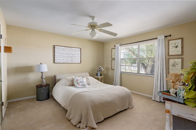 bedroom featuring a textured ceiling, light colored carpet, and ceiling fan