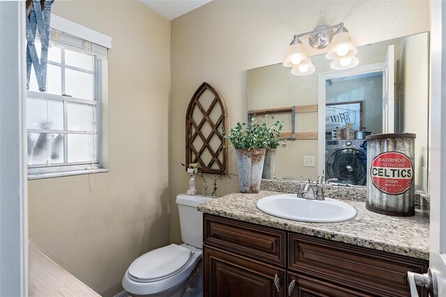 bathroom with toilet, vanity, and washer / dryer