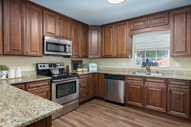 kitchen featuring stainless steel appliances, sink, light stone counters, and dark hardwood / wood-style flooring