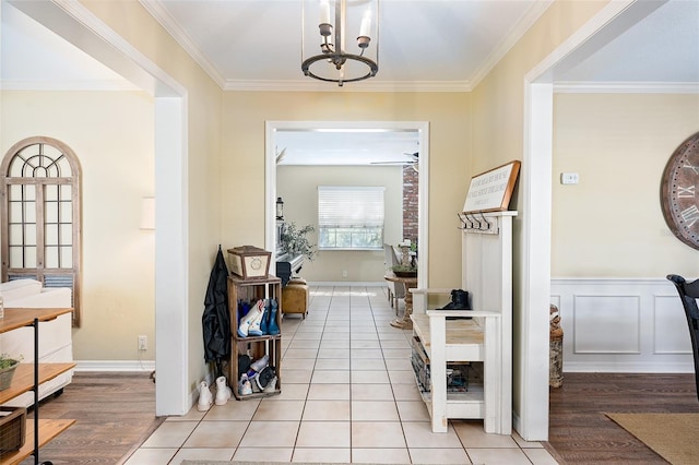 corridor with light wood-type flooring, a chandelier, and ornamental molding