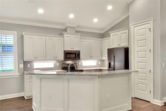 kitchen with lofted ceiling, a center island with sink, white cabinetry, hardwood / wood-style flooring, and stainless steel appliances