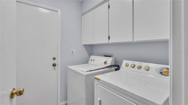 clothes washing area with washing machine and clothes dryer and cabinets