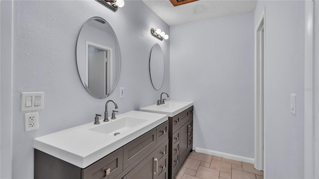 bathroom featuring a textured ceiling, tile floors, dual sinks, and vanity with extensive cabinet space