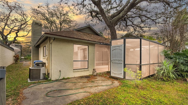 back house at dusk with central air condition unit and a patio