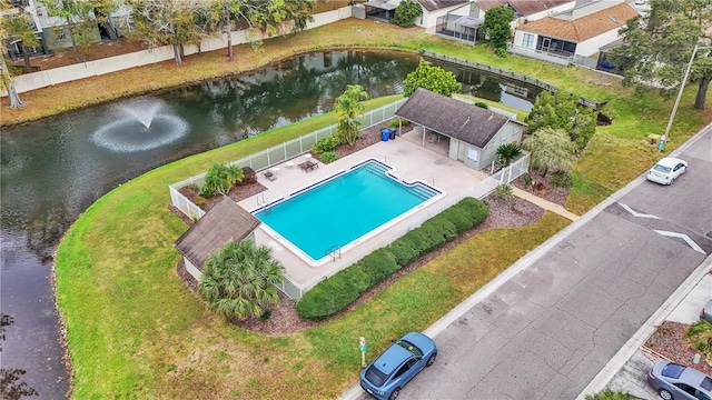 view of swimming pool featuring a water view, a yard, and a patio