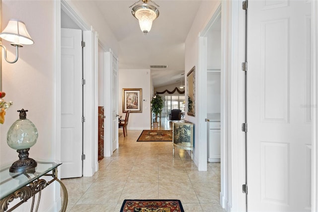 hall with light tile floors and vaulted ceiling