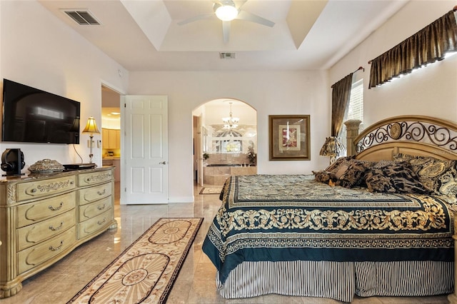 tiled bedroom featuring a raised ceiling, connected bathroom, and ceiling fan with notable chandelier