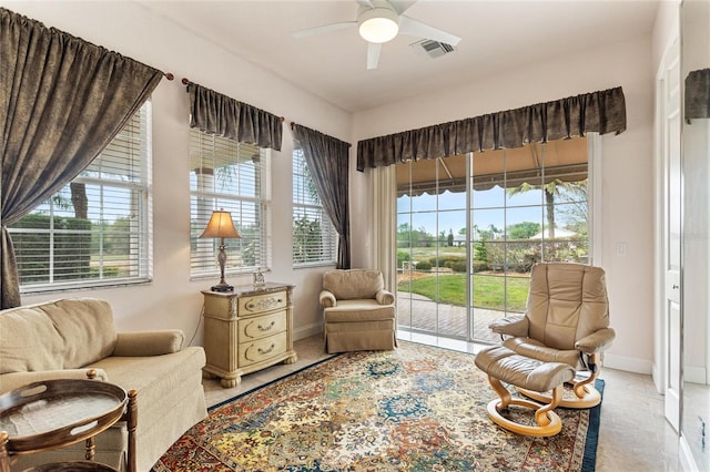 living area with light tile floors and ceiling fan