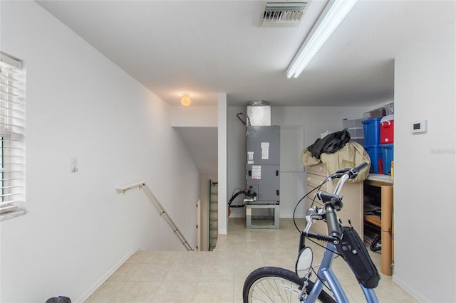 exercise area featuring light tile floors and heating utilities