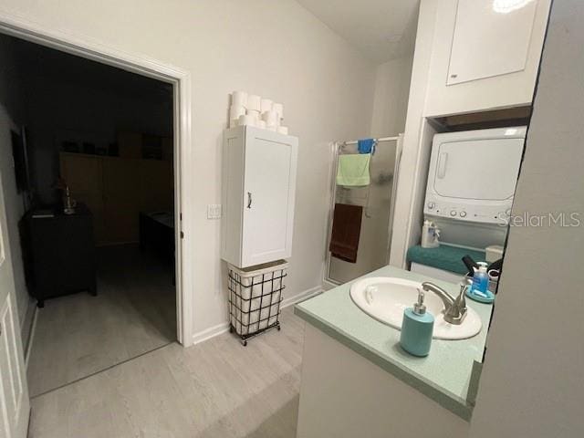 bathroom with hardwood / wood-style flooring, vanity, and stacked washer and clothes dryer