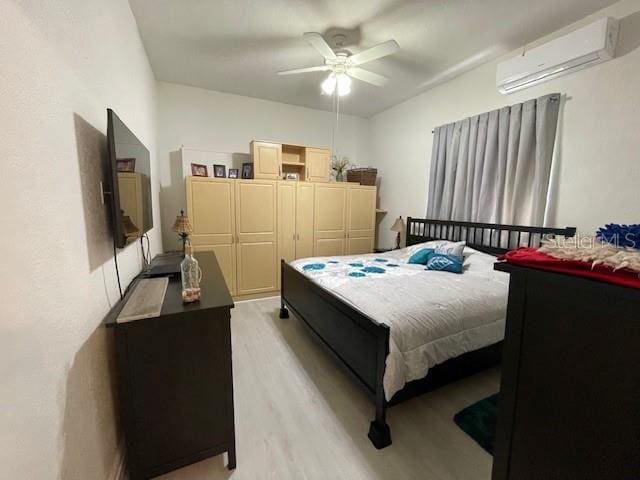 bedroom with ceiling fan, light wood-type flooring, and a wall unit AC