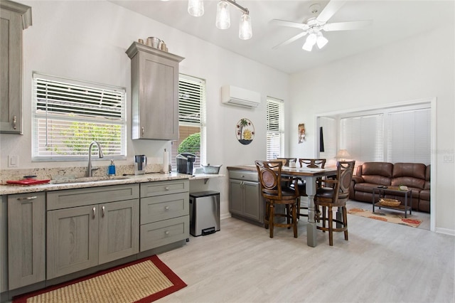 kitchen featuring ceiling fan, sink, light stone countertops, and light wood-type flooring