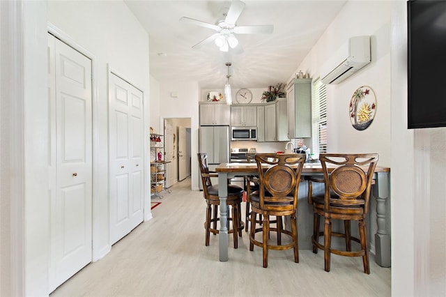 dining room featuring a wall mounted air conditioner, light hardwood / wood-style floors, and ceiling fan