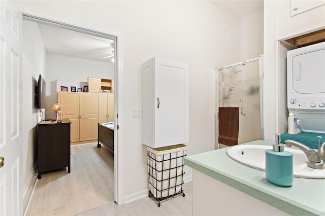 bathroom featuring vanity, stacked washer and dryer, ceiling fan, and hardwood / wood-style flooring