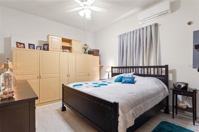 bedroom with light hardwood / wood-style floors, ceiling fan, and an AC wall unit