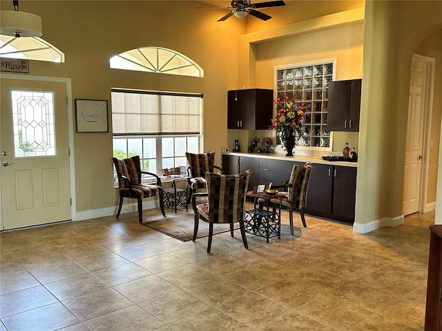 dining area featuring ceiling fan, light tile floors, and a towering ceiling