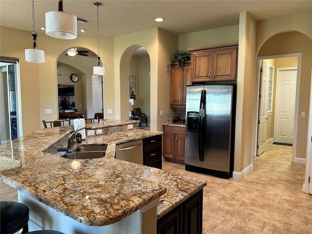 kitchen with stainless steel appliances, light stone countertops, light tile floors, and decorative light fixtures