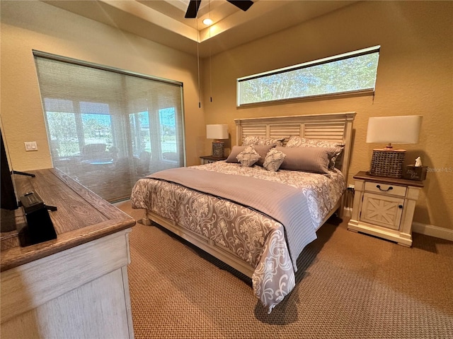 carpeted bedroom with ceiling fan and a tray ceiling