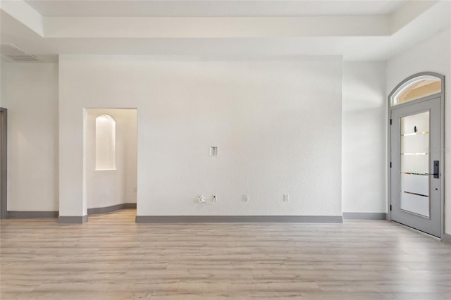 unfurnished room with a raised ceiling and light hardwood / wood-style flooring