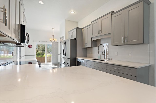 kitchen featuring pendant lighting, sink, gray cabinets, a chandelier, and stainless steel appliances