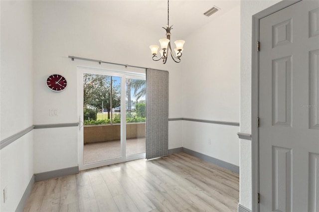 unfurnished room featuring a chandelier and light hardwood / wood-style flooring