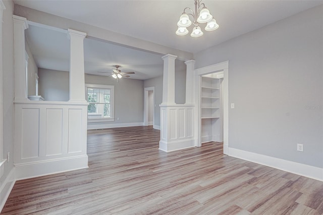 spare room featuring ornate columns, ceiling fan with notable chandelier, and light hardwood / wood-style flooring