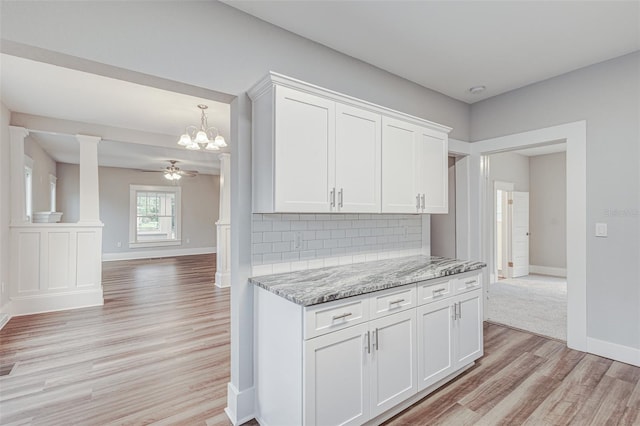 kitchen featuring white cabinets, backsplash, ceiling fan with notable chandelier, and light wood-type flooring