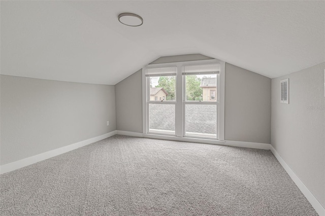 additional living space featuring vaulted ceiling and light colored carpet