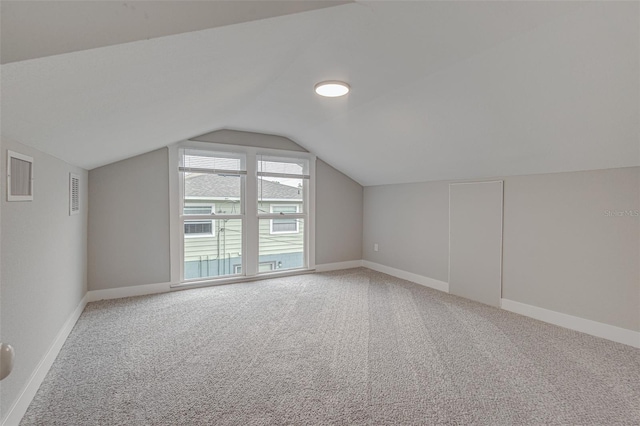 additional living space with light colored carpet and vaulted ceiling