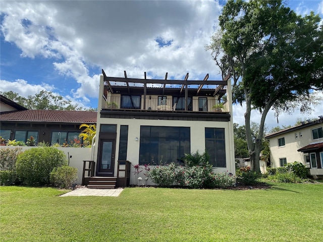 rear view of property with a lawn and a balcony