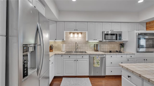 kitchen featuring dark hardwood / wood-style floors, sink, stainless steel appliances, tasteful backsplash, and white cabinetry