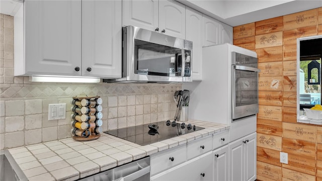 kitchen with white cabinetry, backsplash, tile countertops, and black electric cooktop