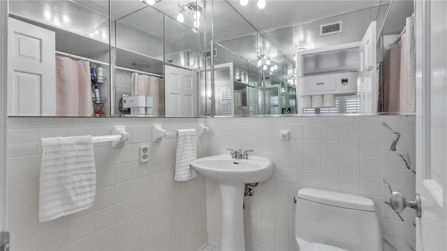 bathroom featuring tile walls, backsplash, and toilet